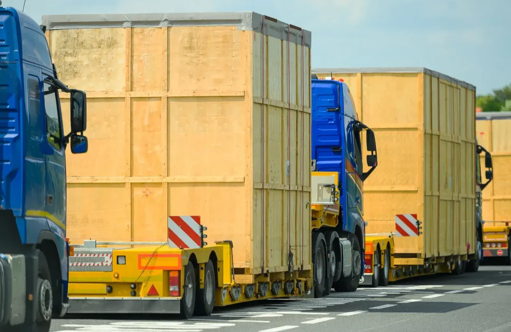 trucks moving huge wooden boxed